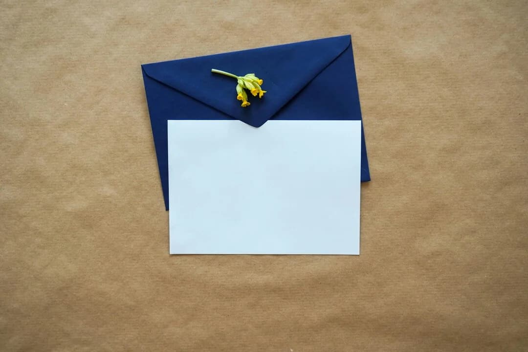 Une carte vierge avec une enveloppe bleue et une petite fleur jaune.