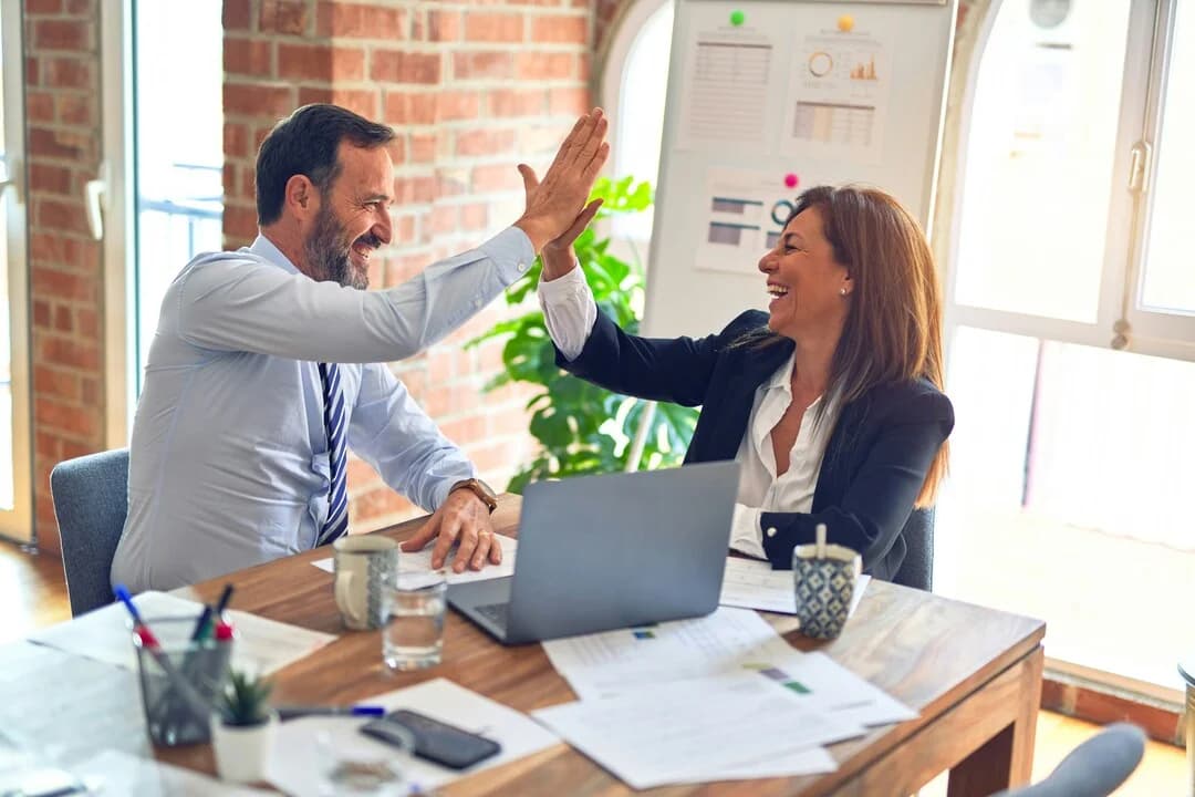 Two colleagues high-fiving over a work table.