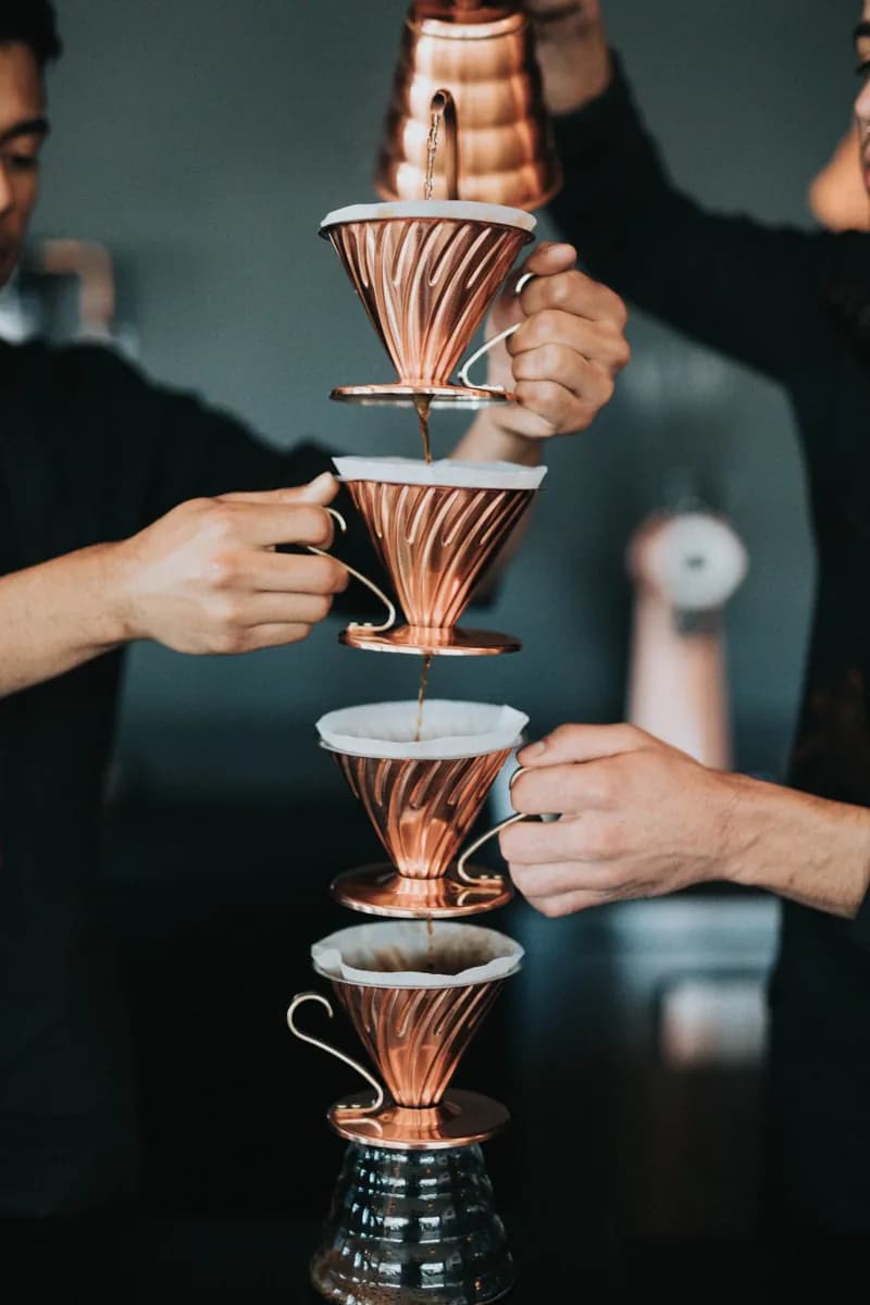Hands holding a vertical stack of coffee drippers.