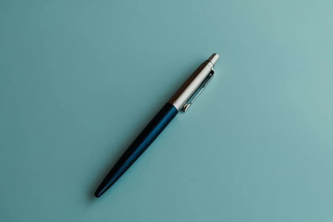 A single pen on a plain turquoise surface.