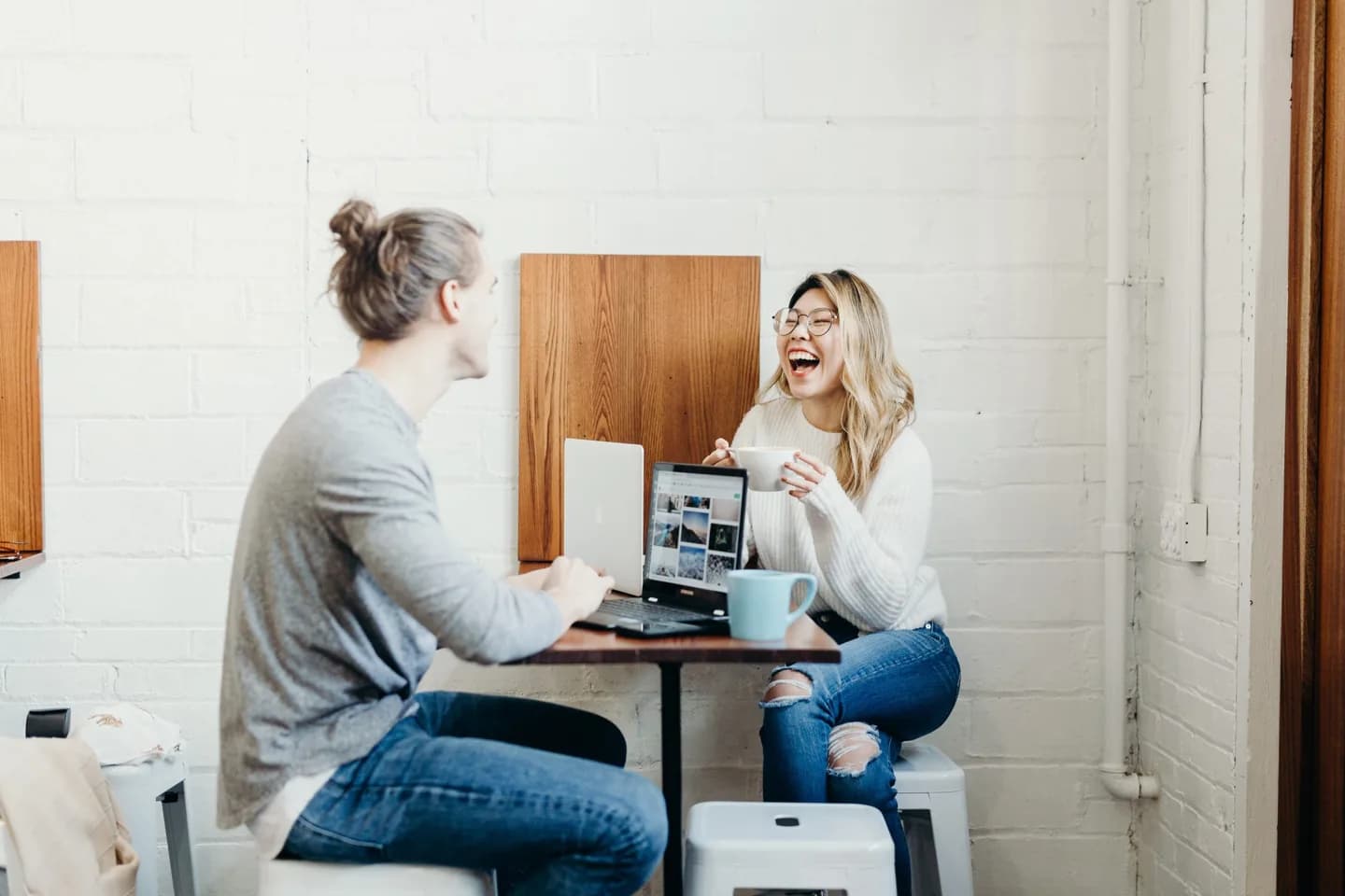 Two people talking at a table with a laptop.