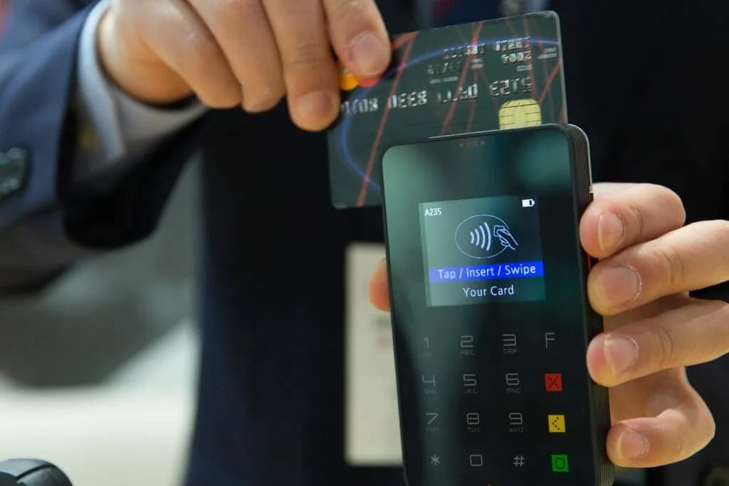 A payment card held above a card terminal.