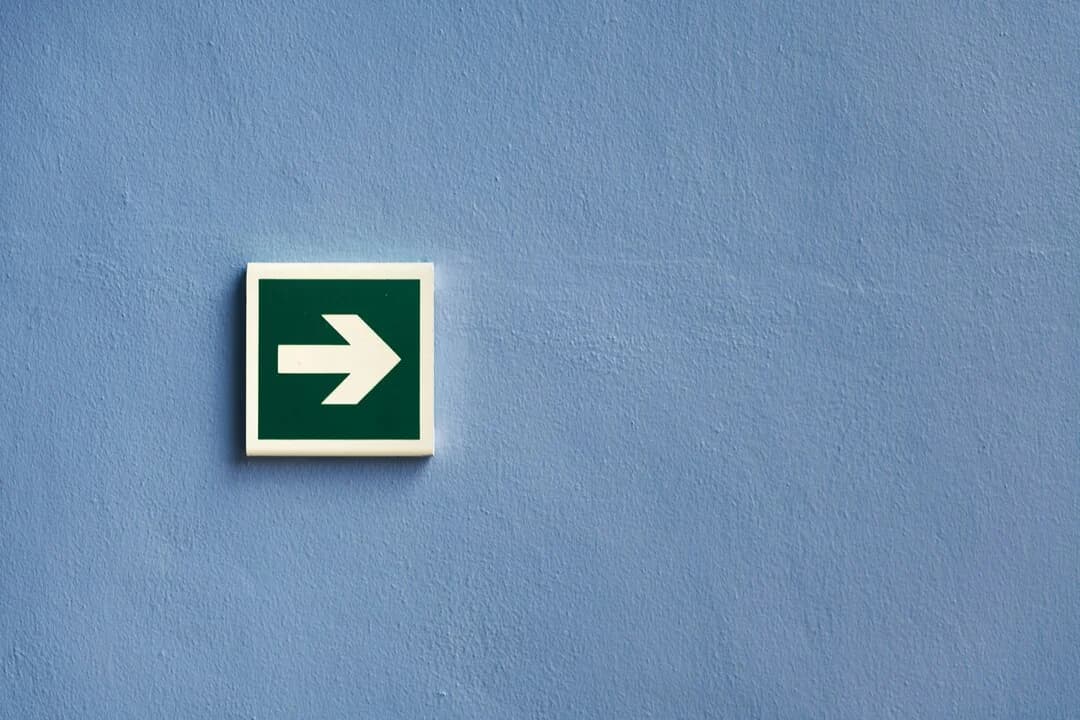 Une flèche directionnelle verte sur un mur bleu.