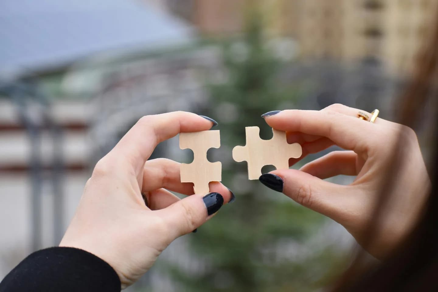 Two hands bringing puzzle pieces together.