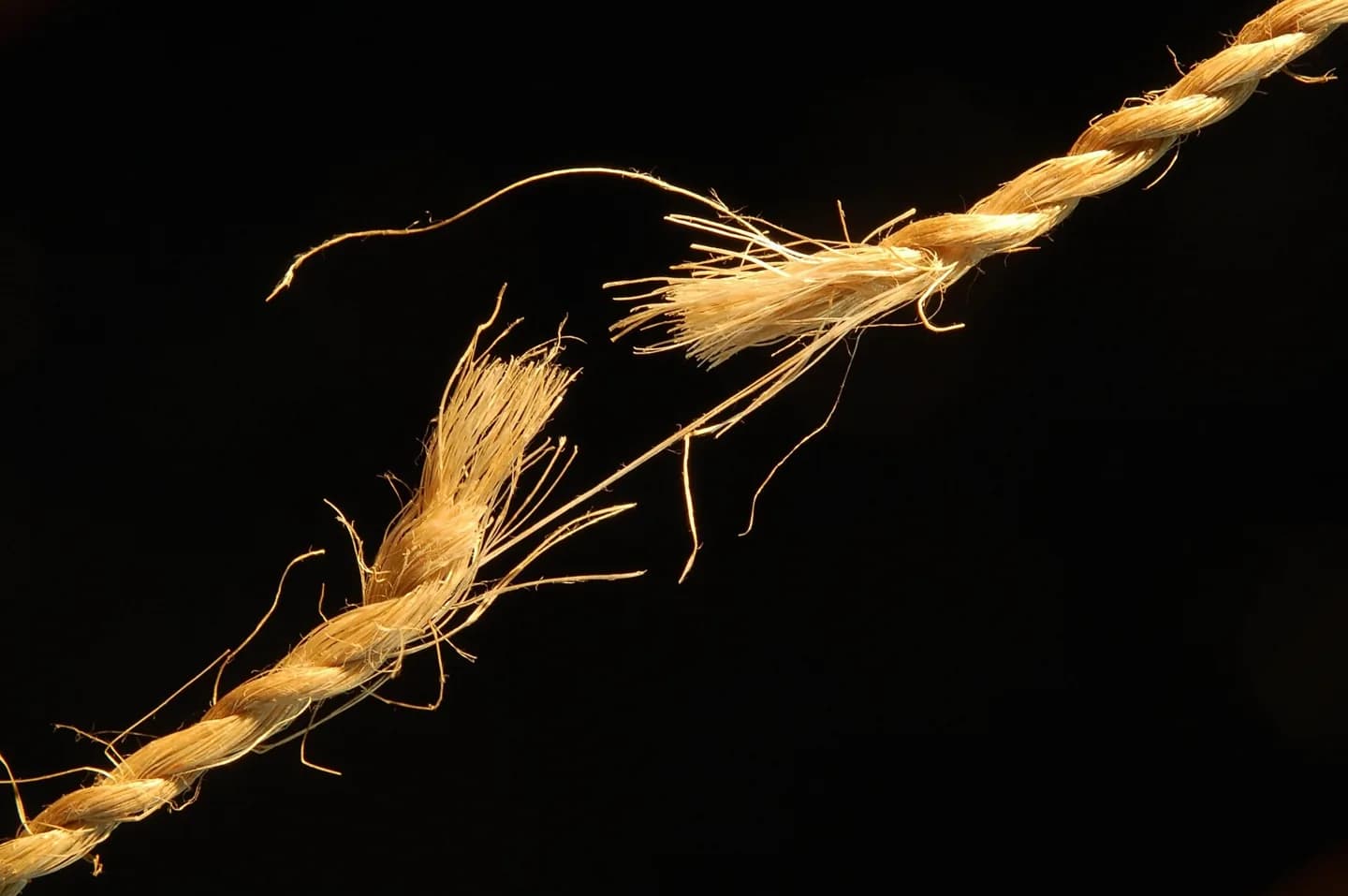 A fraying rope stretched against a dark background.