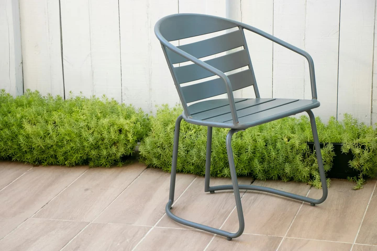 An empty metal chair beside a wall.