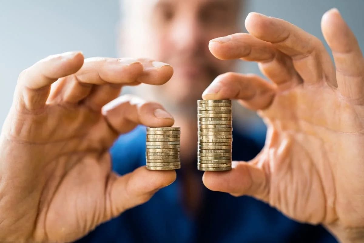 Hands comparing two stacks of coins.