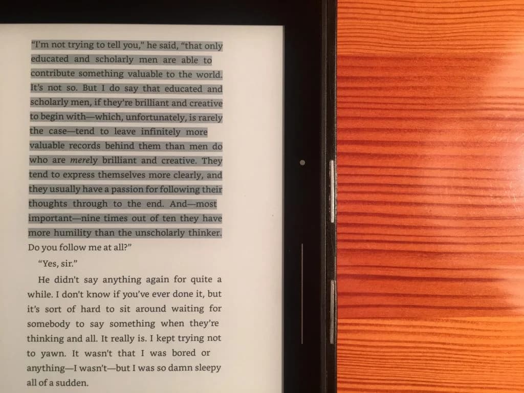 An electronic reader displaying a page of text beside an orange cover.