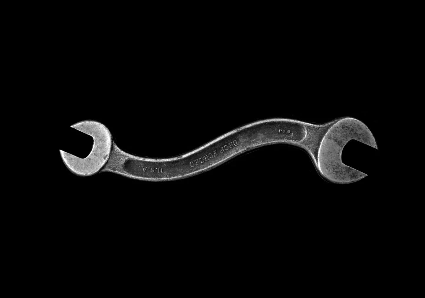 A double-ended spanner on a black background.