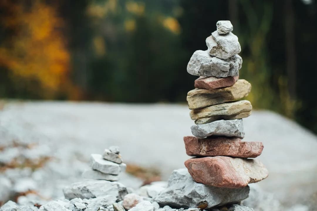 A tower of balanced stones beside water.