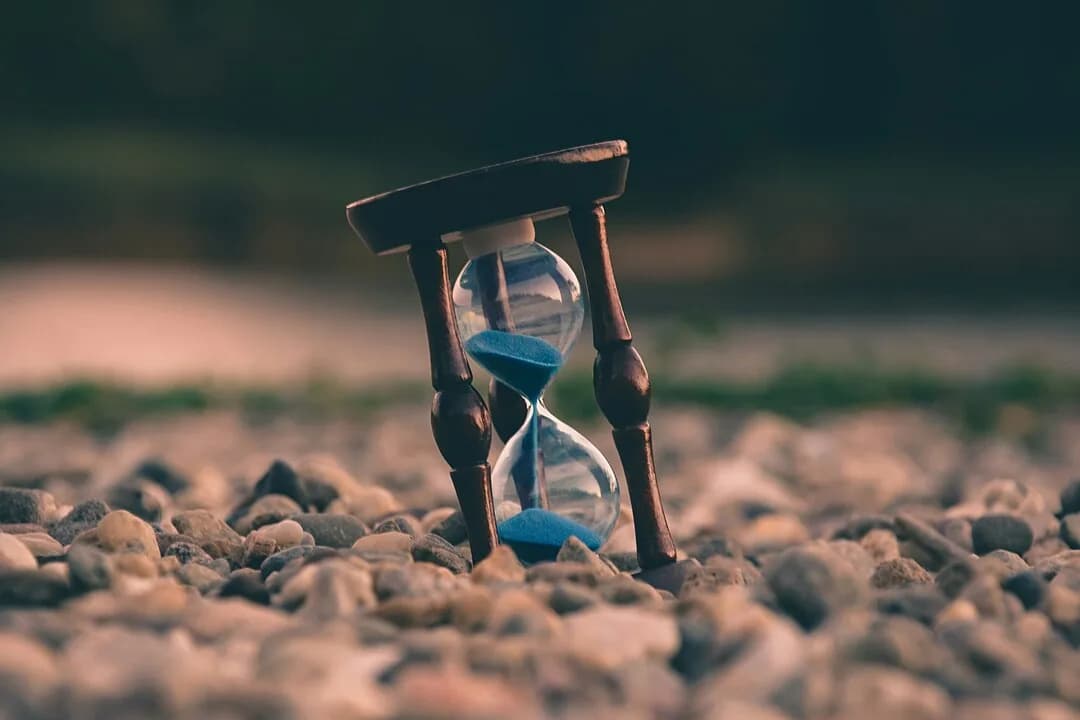 An hourglass resting on small stones.