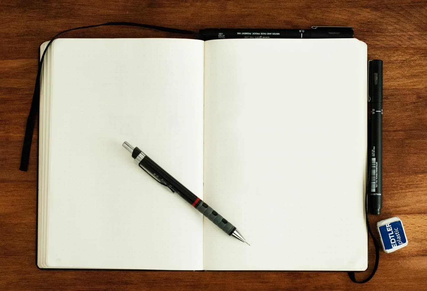 An open blank notebook with a pen on a wooden desk.