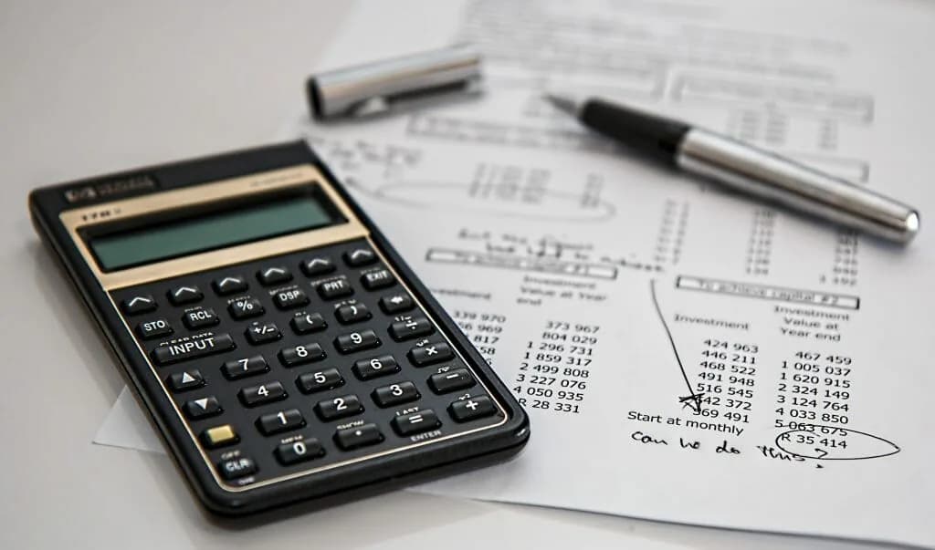 A calculator and pen on printed financial documents.