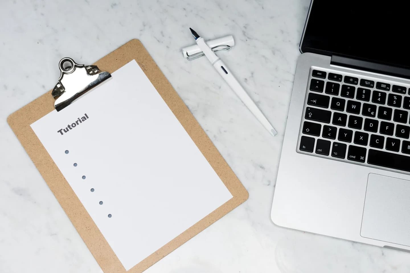 A clipboard, laptop and calliper on a desk.